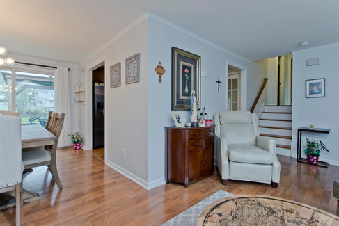 A corner look of the dinging room and living room that open into each other. Stairs lead up the split level.