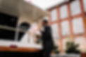 Bride on the balcony of a vintage wedding trolley kissing a groom standing on the back