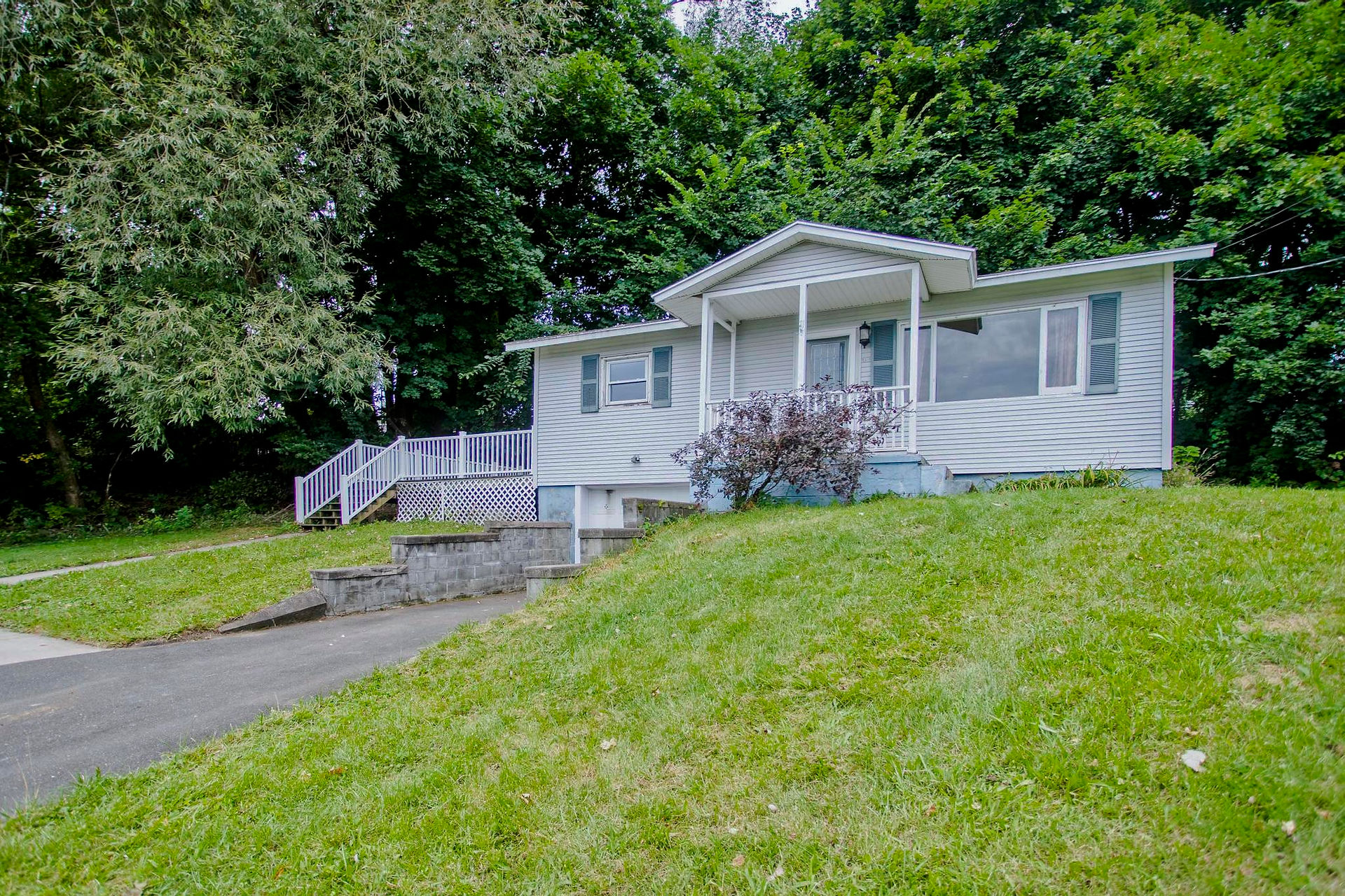 A photo of 11 Sylvia Lane in Holyoke, MA. It's a 1 car garage raised ranch with white siding and dark grey shutters. There's a big deck and small porch. This is an angled shot