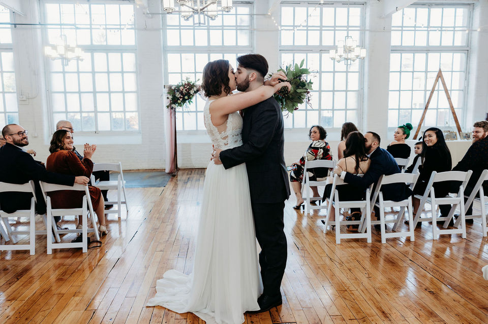 The couple kisses in front of the iconic historic windows at the Boylston Rooms.