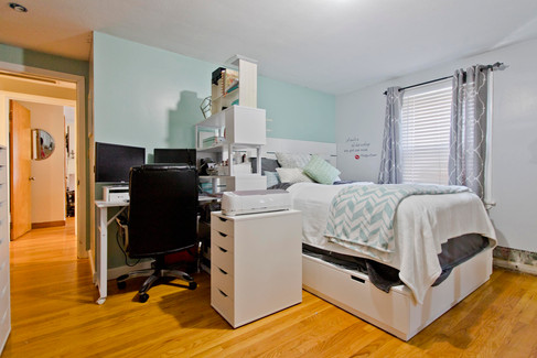 One of the bedrooms, it has a bright window and a ceiling fan. The walls are blue. There's a huge flatscreen TV and a queen sized bed.