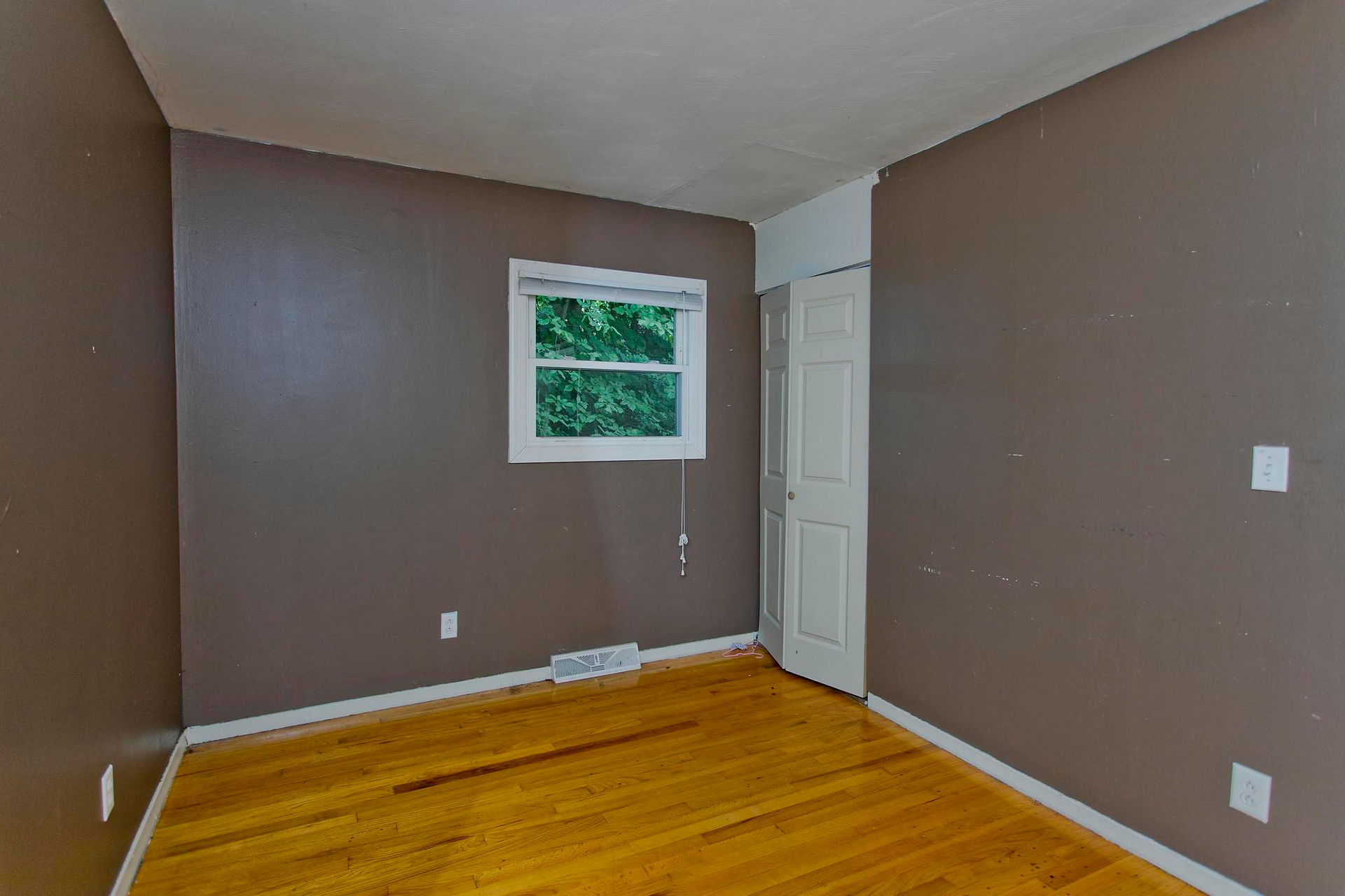 A brown bedroom with white trim and several bottom slider windows in this Holyoke home centrally located between Northampton and West Springfield. 