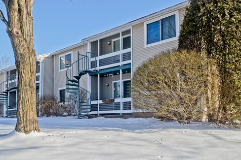 Located in Holyoke, rear view of balcony of the condo. It has a spiral staircase and tan siding. 