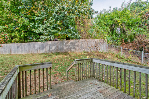 A view of the backyard, wooden fence and chain link fence on one side from the small wooden deck off the kitchen.