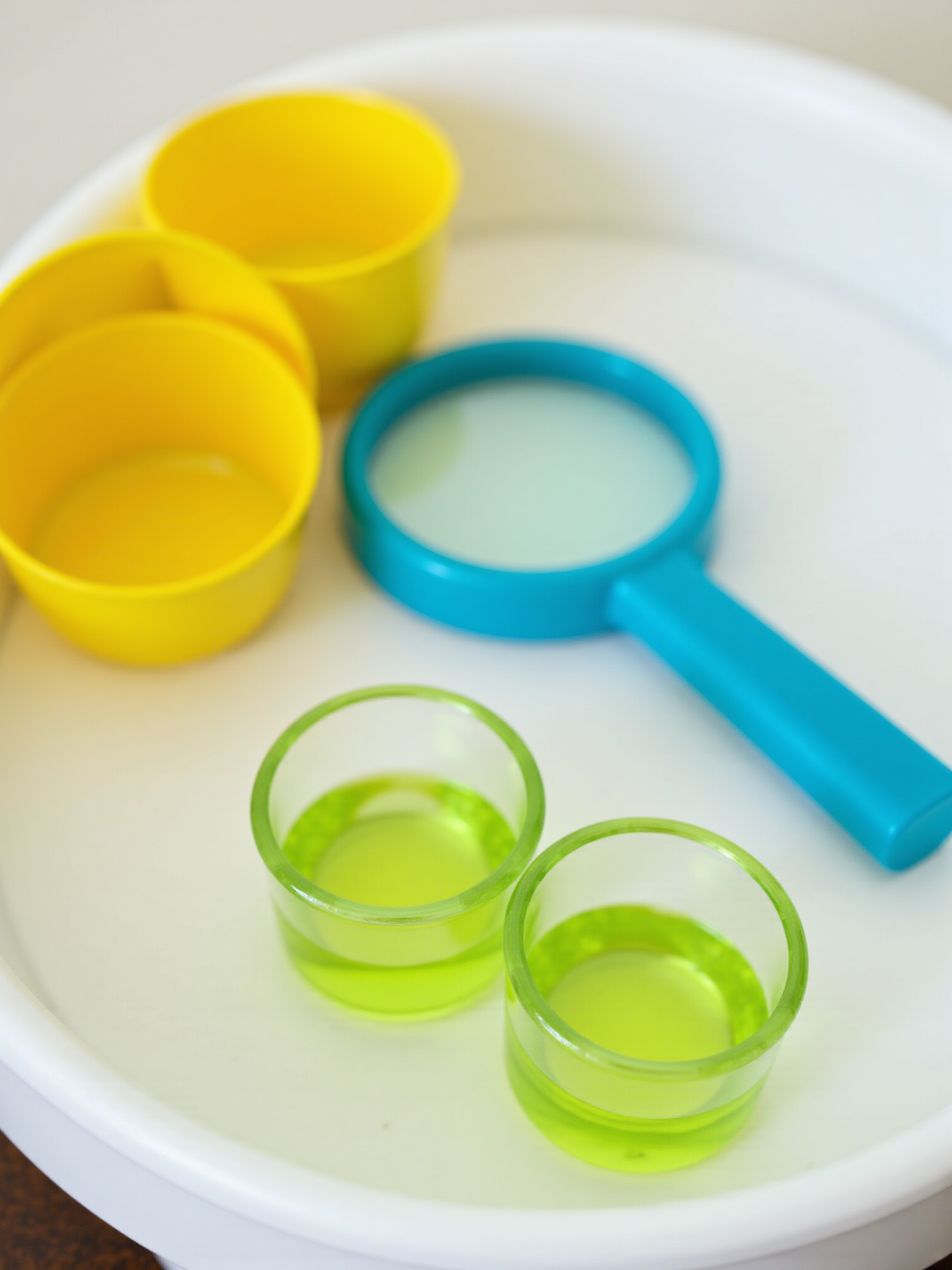 child's magnified glass and bright colored objects for review