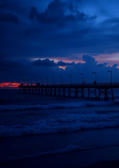 Ocean fishing pier at sunset with dark m