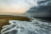 A dramatic seascape with turbulent waves meeting a darkening sky, capturing the moment calm turns to chaos.