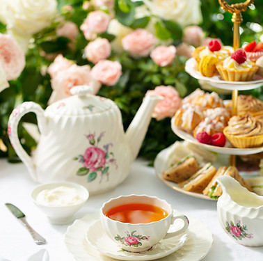 Afternoon tea table Assortment of cakes, sweets and sandwiches Rose garden background.jpg