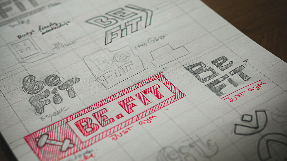Sketches of "Be Fit" logo designs on paper, featuring various styles. A prominent red design reads "BE.FIT" with "Just Gym" below.