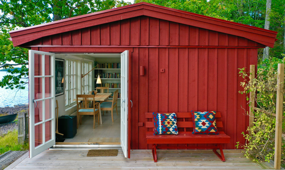 Röd stuga med öppna altandörrar och sittbänk – byggfirma nybyggnation och altan Småland