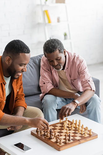A father and his adult son playing chess after having their air conditioning unit replaced in New Cumberland, PA by Daflure Heating Cooling and Solar