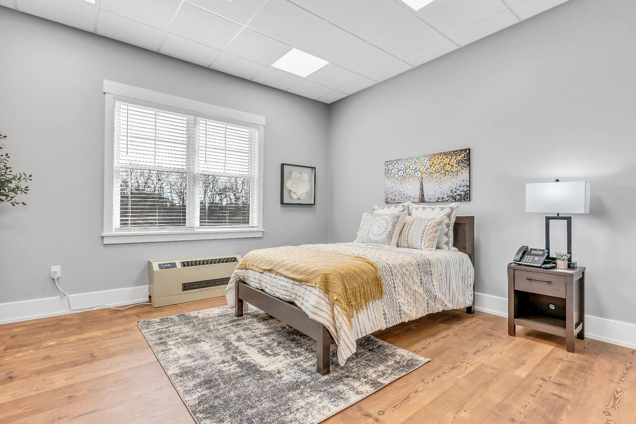 Bedroom with artwork up and a rug on the floor at Silver Spring Personal Care Home