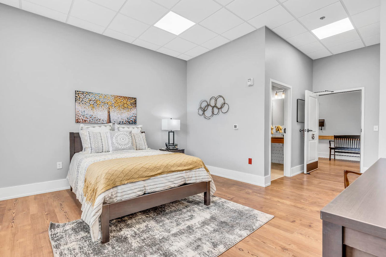 Senior care bedroom with wall art and a yellow blanket at the foot of the bed