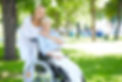Senior woman in a wheelchair with her young woman caregiver hugging her from behind