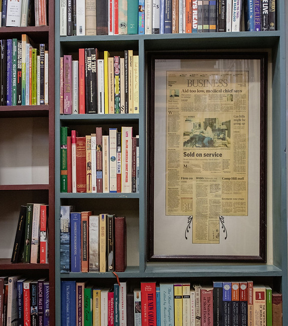 Books around a framed newspaper article that features Cupboard Maker Books with the headline "Sold on service."