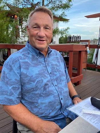 Mike Howell, founding board member of Promise Landing Farm, sitting outside at a dinner table