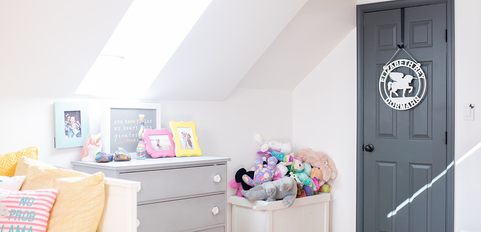 Girls bedroom showcasing a personalized sign on the door with a unicorn pegasus in the middle