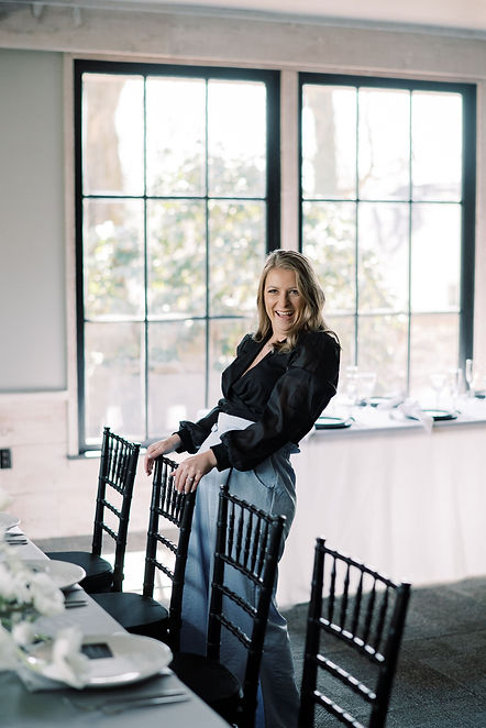 Unique by Design owner and lead planner, Jenna Saunders, leaning back with her hands over a chair laughing.