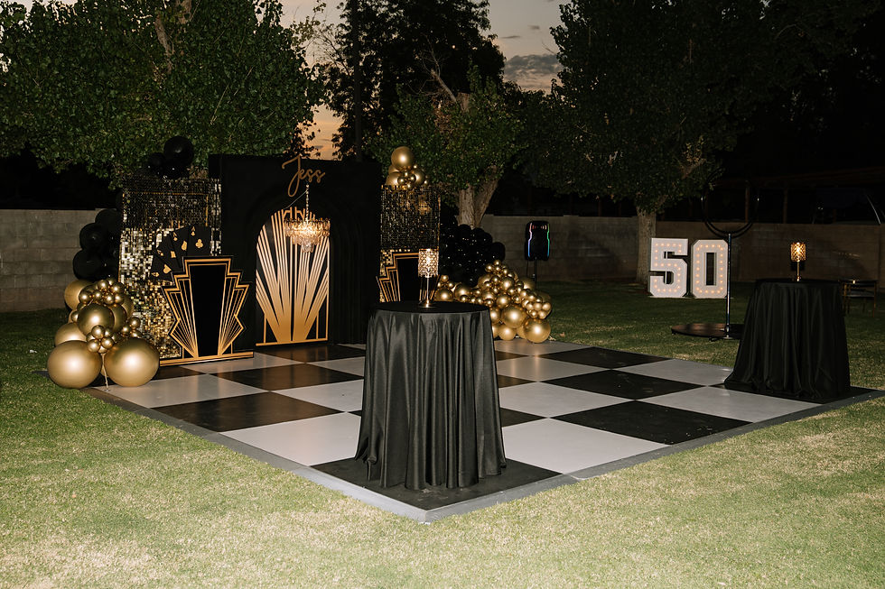 Wide view of Gatsby-themed birthday party backdrop with black and gold balloons, shimmer walls, and checkered dance floor.