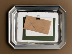Enveloppe kraft et papier posés dans un plat en inox