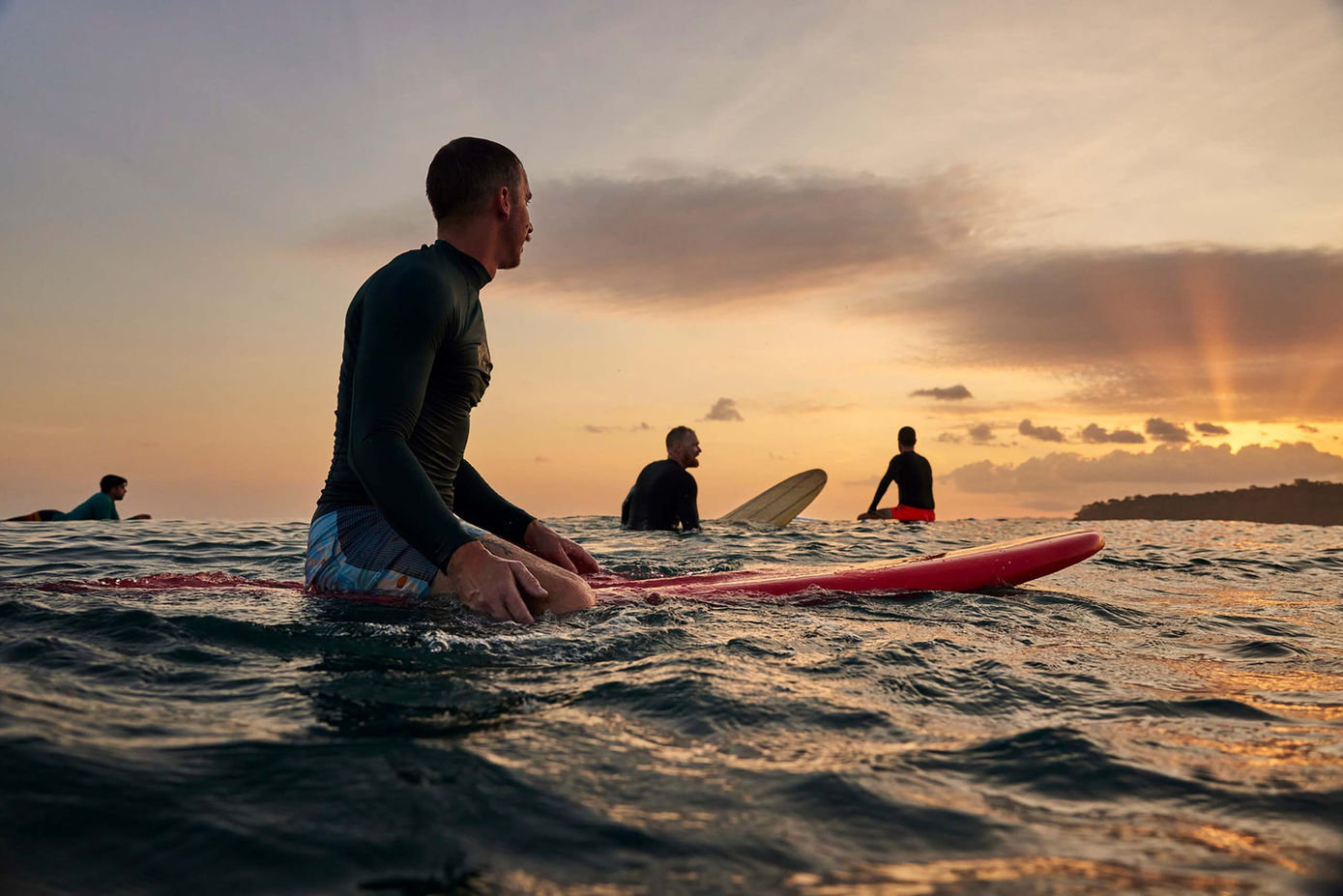 Surfers in the water staring at the sunset