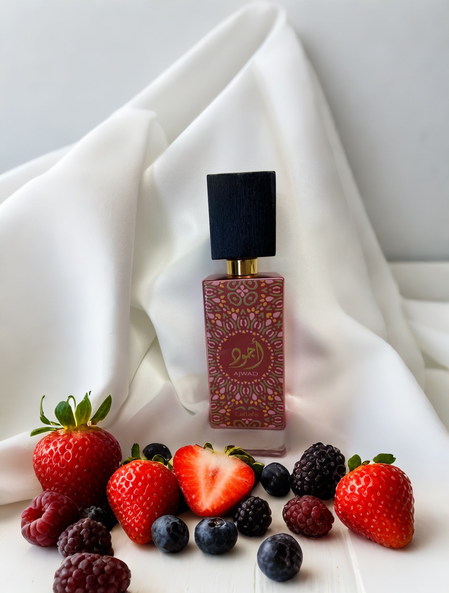 flacon avec details orientaux entoure de fruits rouges en reference aux notes olfactives