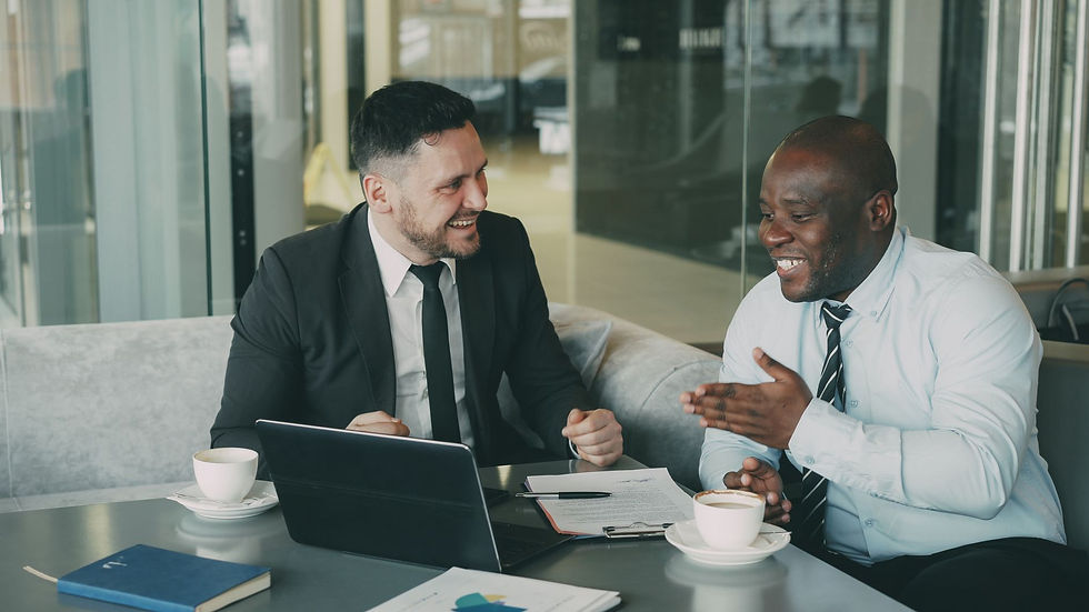 Two businessmen laughing and discussing work in a modern office setting.