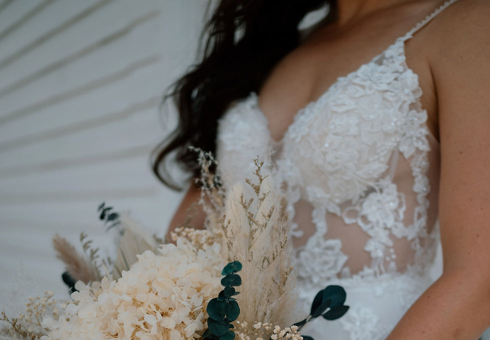 Torso of bride in wedding dress holding pampas flower bouquet