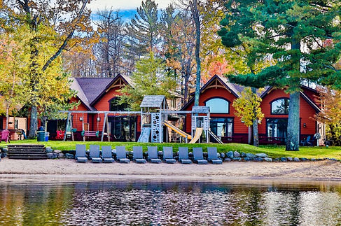 beach lake water lounge chairs playground with slide and swings cabins woods in back