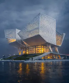 The-Stitches: Iconic contemporary waterfront architecture featuring a sculptural façade and illuminated interior, showcasing innovative urban design by WiEdesign.