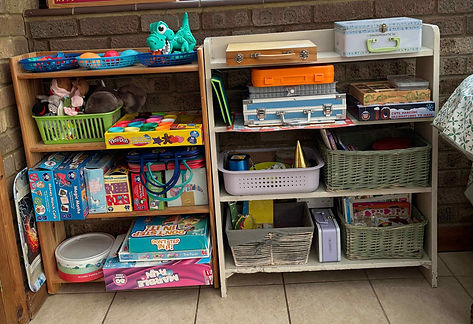 Organised shelves with games and arts and crafts in a playroom.