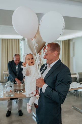 Vauva ihmettelee ilmapalloja isän sylissä ristiäisten valokuvauksessa. Juhlapaikkana on Pyhän Henrikin katedraali Helsingissä.