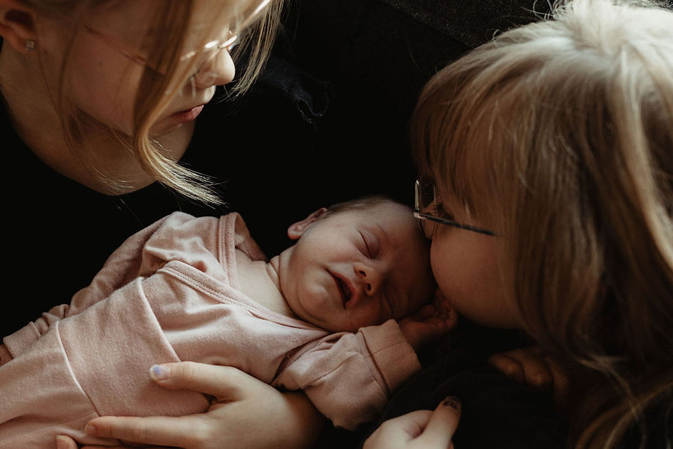 Vauva sisarusten sylissä perhekuvauksissa