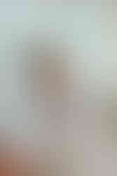 Äiti pitää vauvaa sylissään kastejuhlan valokuvauksessa. Pöydällä on iso kakku.