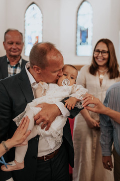 Isä antaa suukon vauvalle ristiäisissä kastetilaisuuden jälkeen. Ristiäisten valokuvaus on toteutettu Helsingissä.