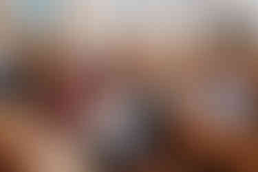 Vauva hymyilee kastejuhlassa kameraan katsoen, muu juhlaväki katsoo pappia kohti