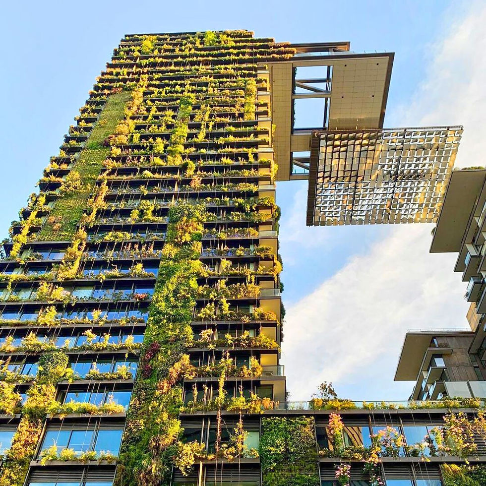 Rascacielos cubierto de vegetación en un día soleado. Fachada verde, cielo azul y estructura metálica flotante a la derecha.