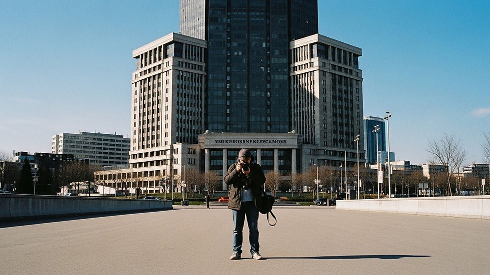Persona tomando foto frente a edificio alto bajo cielo azul. Texto borroso en edificio, ambiente tranquilo y despejado.