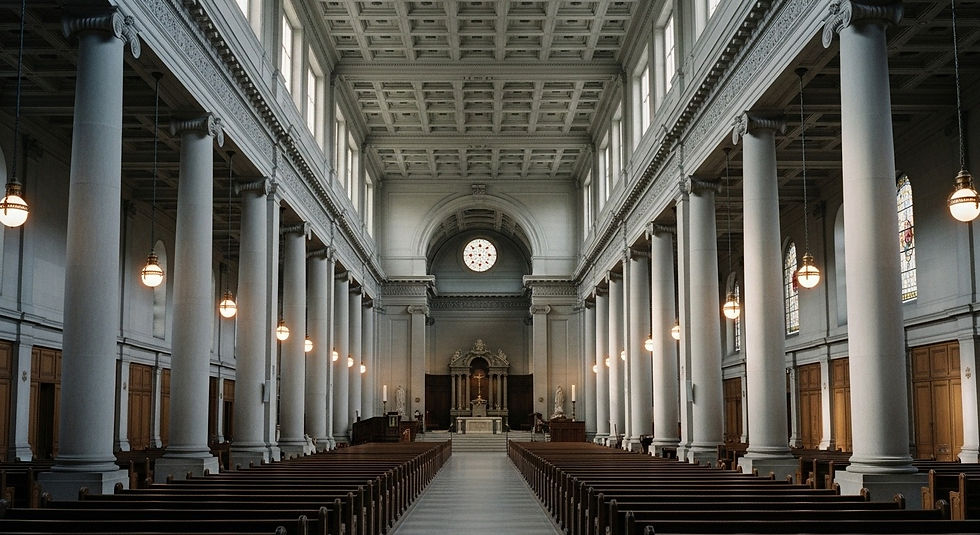 Interior de una iglesia con columnas blancas y bancos de madera. Luz cálida de lámparas colgantes. Ventanas con vitrales. Ambiente solemne.