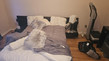 Messy bedroom with unmade bed, pillows, and fitness equipment