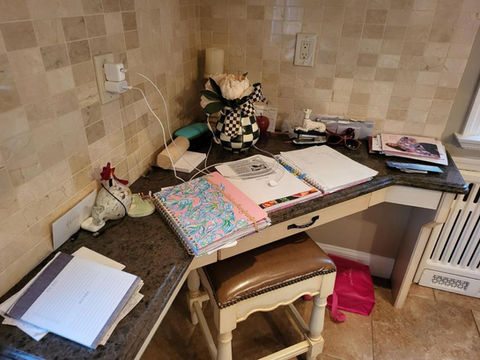 Kitchen desk with papers, notebooks, and phone
