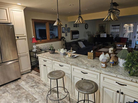 Kitchen island with granite countertop, white cabinets, and two stools