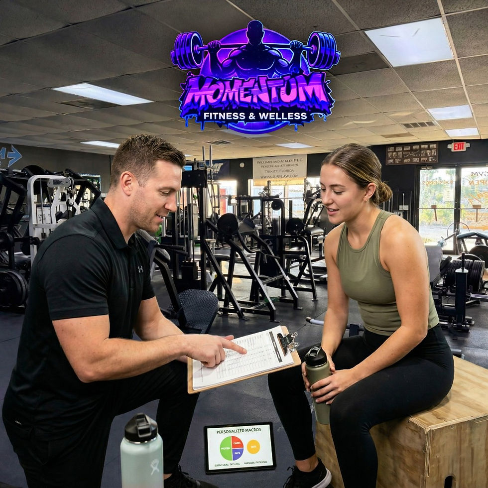 A man in a black shirt kneeling and holding a clipboard to show data to a woman sitting on a wooden box, with a sign in the background reading "MOMENTUM FITNESS & WELLNESS".