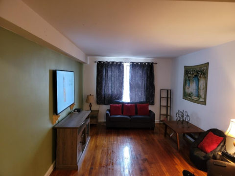 Living room with hardwood floors, TV, couch, and tapestry