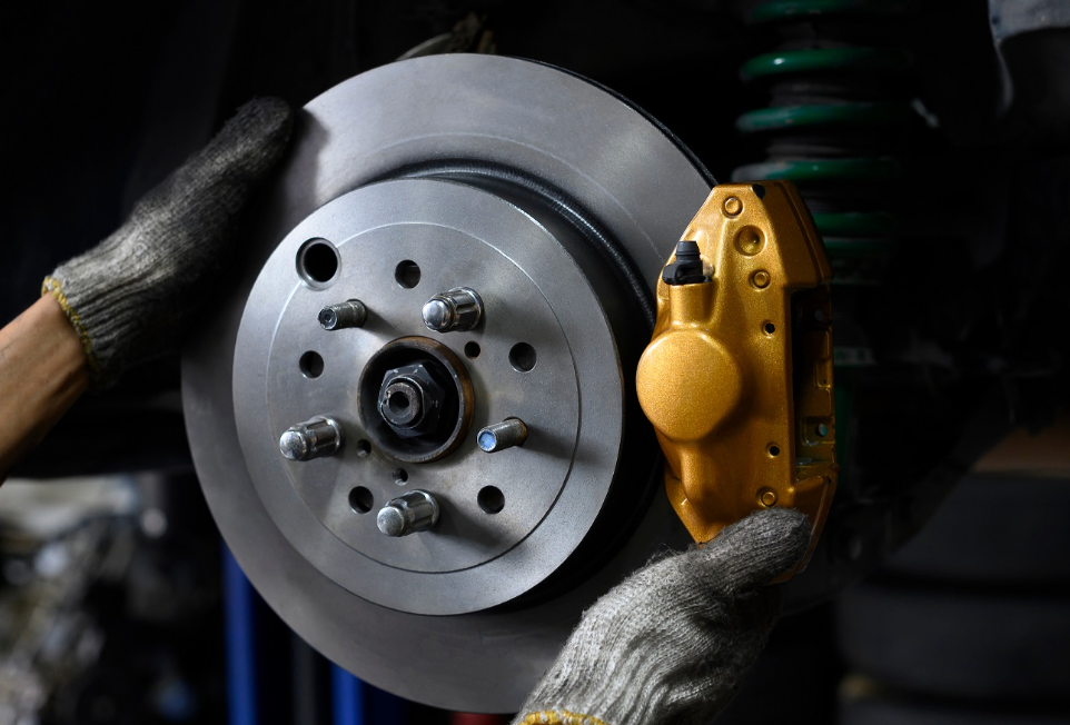 Close-up of brake pads and rotors being inspected by a mechanic