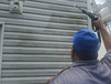 Worker pressure washing dirty siding