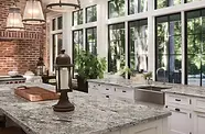 Modern kitchen with white island, granite counters, and skylights