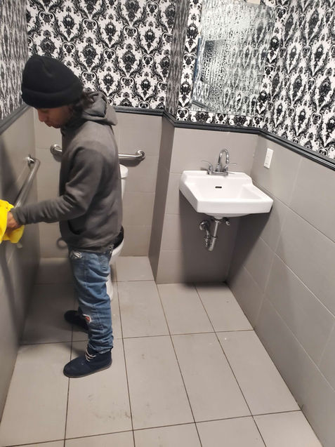 Person cleaning restroom, gray floor, sink