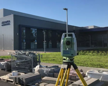 Ģeodēziskais instruments pie industriālas ēkas