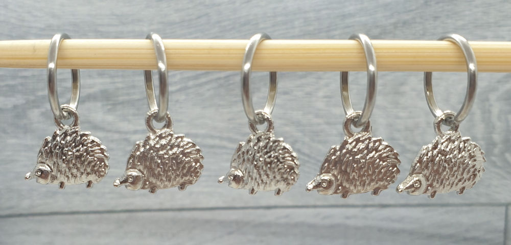 5 hedgehog shaped silver metal coloured charms with rings on knitting needle